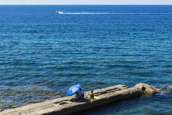 Hombre y una mujer sentados en una pared de piedra en el mar —  Fotos de Stock