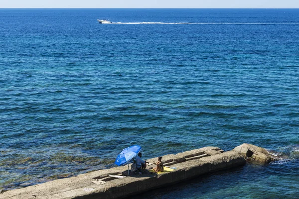 Homem e uma mulher sentados em uma parede de pedra no mar — Fotografia de Stock