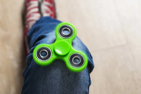 Menina brincando com brinquedo fidget spinner verde — Fotografia de Stock