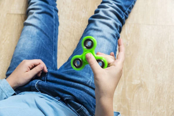 Menina brincando com brinquedo fidget spinner verde — Fotografia de Stock