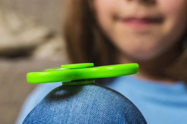 Little girl playing with green fidget spinner toy — Stock Photo, Image