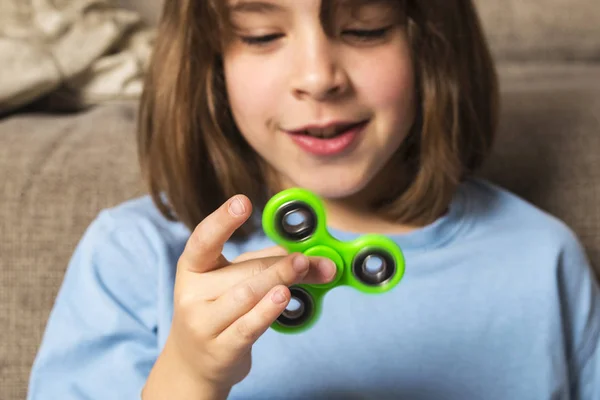 Little girl playing with green fidget spinner toy — Stock Photo, Image