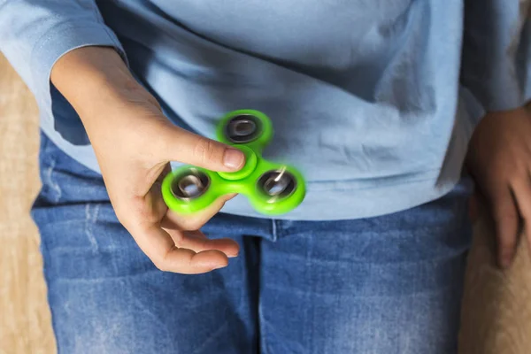 Menina brincando com brinquedo fidget spinner verde — Fotografia de Stock