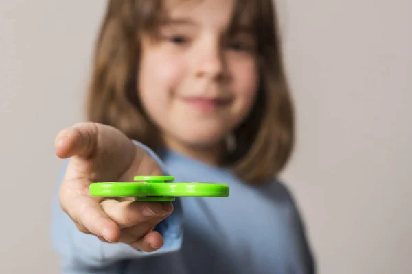 Lille pige leger med grøn fidget spinner legetøj - Stock-foto