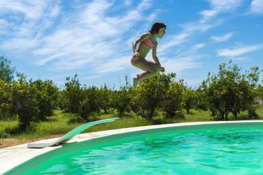 Küçük kız Açık Yüzme havuzunda bir silindirin içinde atlama