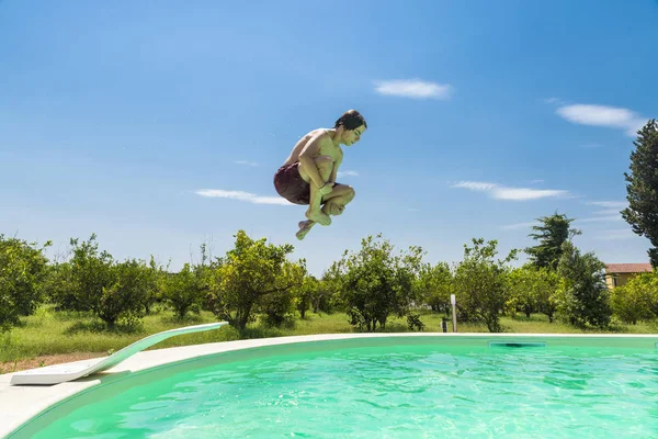 Teen boy jumping in pump in an outdoor pool — Stock Photo, Image