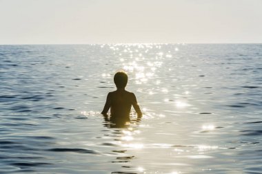 Sunbeam yansıma ile çevrili deniz banyo genç çocuk