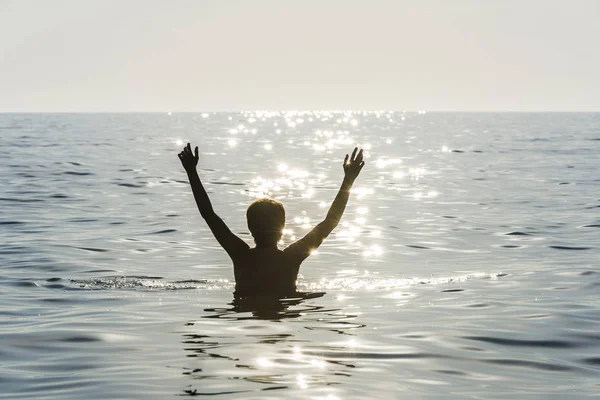 Adolescente niño bañándose en el mar con los brazos levantados —  Fotos de Stock