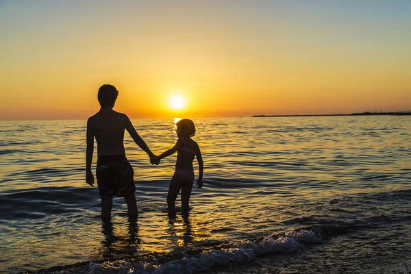 Niña y adolescente bañándose en una playa al atardecer — Foto de Stock