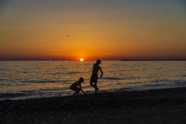 Mała dziewczynka i nastolatek grając na plaży o zachodzie słońca — Zdjęcie stockowe