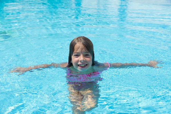 Smiling little girl looking at camera in an outdoor pool — Stock Photo, Image