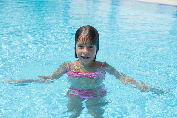 Usměvavá holčička se dívá na kamery ve venkovním bazénu — Stock fotografie