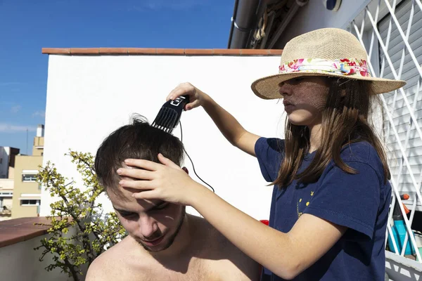 Κοριτσάκι Κόβει Μαλλιά Ενός Έφηβου Αγοριού Κουρευτική Μηχανή Στο Μπαλκόνι — Φωτογραφία Αρχείου