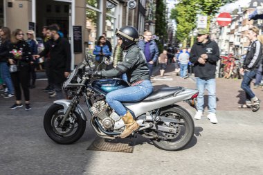 Amsterdam, Hollanda - 7 Eylül 2018: Motosikletli genç bir kadın ve Amsterdam, Hollanda 'nın eski tarihi bir merkezinde yürüyen insanlar