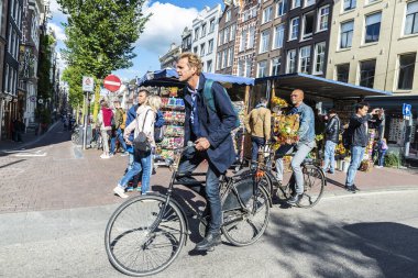 Amsterdam, Hollanda - 7 Eylül 2018: Bisiklet süren adam ve Amsterdam, Hollanda 'nın eski tarihi merkezinde yürüyen insanlar