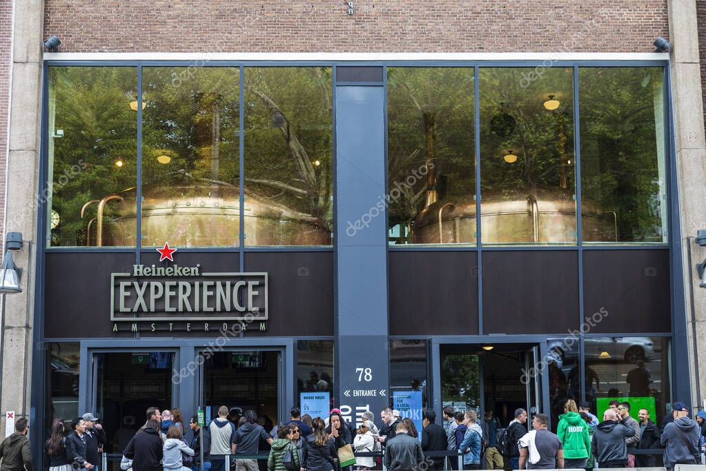 Amsterdam, Netherlands - September 8, 2018: Facade of Heineken brewery headquarters or Heineken Experience with people around in the centre of Amsterdam, Netherlands