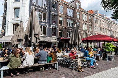 Amsterdam, Hollanda - 8 Eylül 2018: Hollanda 'nın eski Amsterdam kentindeki Gerard Douple caddesinde güneşli bir günde insanların içki içtiği bir bar ve restoranın terası