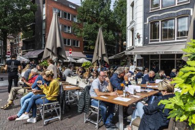 Amsterdam, Hollanda - 8 Eylül 2018: Hollanda 'nın eski Amsterdam kentindeki Gerard Douple caddesinde güneşli bir günde insanların içki içtiği bir bar ve restoranın terası