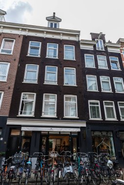 Amsterdam, Hollanda - 8 Eylül 2018: Park halindeki bisikletleri ve eski Amsterdam, Hollanda 'da bir Lois mağazası olan cadde