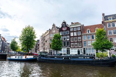 Amsterdam, Hollanda - 8 Eylül 2018: Hollanda 'nın Amsterdam kentindeki eski tekneli bir kanal boyunca eski geleneksel eğimli evler