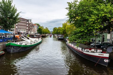 Amsterdam, Hollanda - 8 Eylül 2018: Hollanda, Amsterdam 'da bir kanal boyunca demirlemiş tekneler ve gemiler