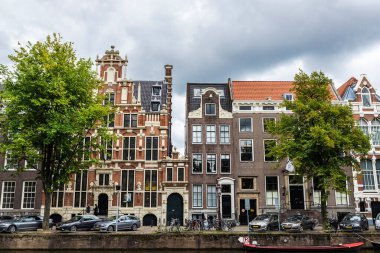 Amsterdam, Hollanda - 8 Eylül 2018: Amsterdam, Hollanda çevresindeki insanların bulunduğu bir kanal boyunca eski geleneksel eğimli evler