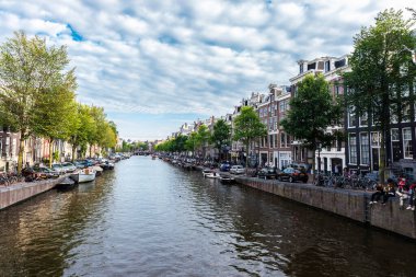 Amsterdam, Hollanda - 9 Eylül 2018: Amsterdam, Hollanda 'da bir kanal boyunca demirlemiş eski geleneksel yassı evler ve insanlar