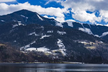 Arkasında yüksek dağlar olan sakin bir göl bahar başlarken kar erimeye başladı..