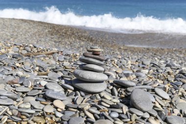dalgalar kıyı şeridine çarpıyor ön planda çakıl yığını var