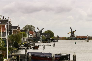 Gölün üzerinde karanlık gökyüzü, yel değirmenleri ve küçük kasabadaki küçük evler.