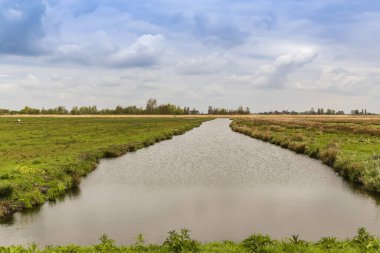 Yerel tarlaları besleyen bir çiftlik nehrinin aşağısına bakın - karanlık ve bulutlu gökyüzü