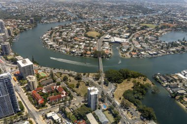 Gold Coast Queensland sahillerinin arkasındaki su yollarına bakan yüksek bir manzara. Sürat teknesi, banliyödeki evlere giden köprüyle denizde iz bırakıyor.