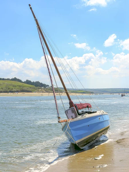Parlak mavi yelkenli, kumlu sahilde küçük dalgalarla karaya vurmuş. Yazın mavi gökyüzü.