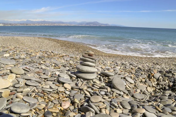 Dalgaları olmayan sakin bir okyanus. Etrafı çakıl taşlarıyla çevrili küçük kumlu bir sahil. Ortasında da çakıl yığını.