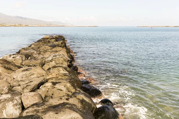Küçük dalgalar ve hafif çamurlu suyla okyanusa inen bir adam.