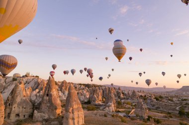 Kapadokya 'nın üzerinde uçuşan pek çok balon gibi güneşin parlak pembe ışığı. Güneşin doğuşunda yüzen sıcak hava balonlarıyla dolu bir vadi..