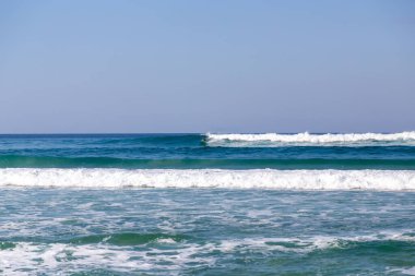 Küçük dalgalar öğleden sonra dalgalanırken sörfçülerden biri dalgalanırken