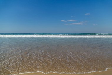 Kumlu sahilde, yaz öğleden sonraları hiç kimsenin olmadığı dalgalar.