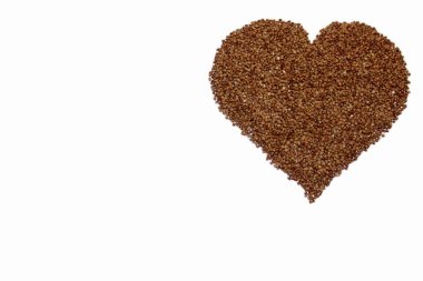 Karabuğday kalbi beyaza izole edilmiş ve yazıya dökülmüş. Ortadaki yeşil karabuğdaydan yapılmış kalp sembolü. Kalp tahıldan yapılmış. Sağlıklı beslenme