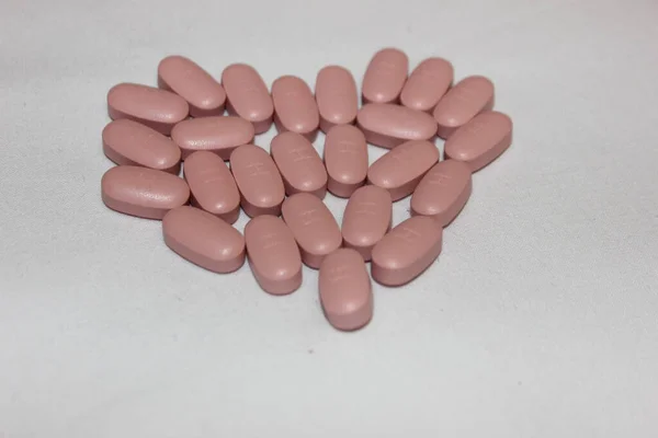 心臓は青と茶色の錠剤で作られました 異なる色の錠剤で作られた心臓は白に隔離された テキスト用のコピースペース 鎮痛剤 治療薬 中毒の概念 — ストック写真