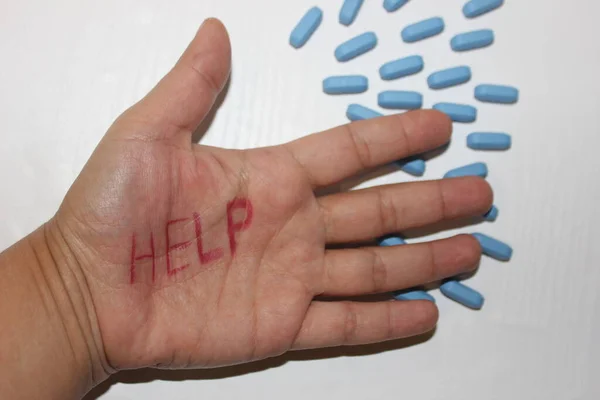 The inscription Help on the hand against the background of pills. Sick person needs help