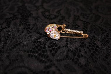 Siyah arka planda büyük takma elmaslar. Dantelli arka planda taşlar olan broş. Broş şeklinde kadın mücevherleri..