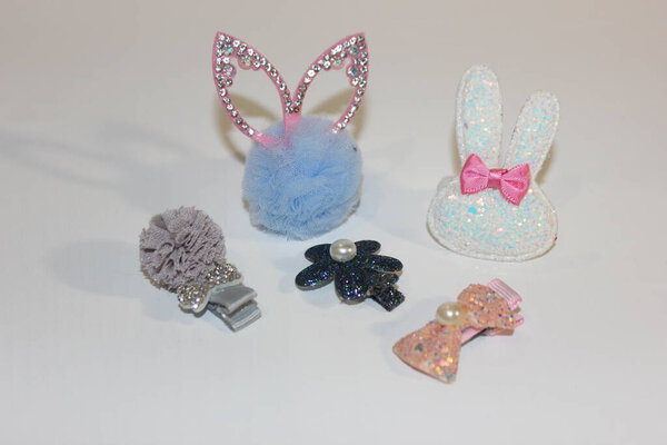 Эластичность и шпильки на белом фоне. Детские украшения для волос. Аксессуары для девочек возле гроба. Парикмахерские, серьги, кольца сокровища маленькой девочки. Детские украшения
