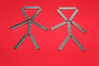 Adam zımba için zımbaları dizdi. Kırmızı arkaplandaki parantezlerden yola çıkarak. Ofisteki adam..