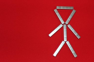 Adam zımba için zımbaları dizdi. Kırmızı arkaplandaki parantezlerden yola çıkarak. Ofisteki adam..