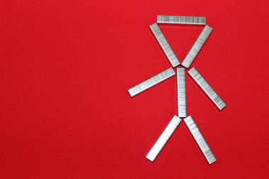 Adam zımba için zımbaları dizdi. Kırmızı arkaplandaki parantezlerden yola çıkarak. Ofisteki adam..