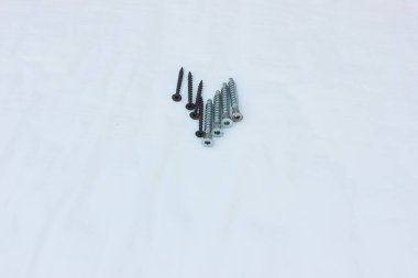 Beyaza izole edilmiş çelik cıvata yığını. Kendi kendini beceren vidalar beyaz arka planda merkezde. Cıvatalara, metal cıvatalara yakın çekim.