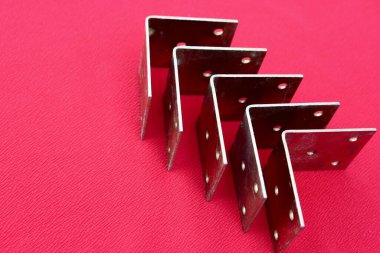 Pembe üzerine izole edilmiş parantezlerden yapılmış ok. Metal köşeler yazı için bir yer ile yukarı yönelir. Kırmızı arka planda altın metal parantez. Metal köşeler, çerçeveler, sınırlar. İzole edilmiş.