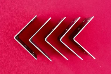 Pembe üzerine izole edilmiş parantezlerden yapılmış ok. Metal köşeler sola dönük ve metin için bir yer var. Kırmızı arka planda altın metal parantez. Metal köşeler, çerçeveler, sınırlar. İzole edilmiş.