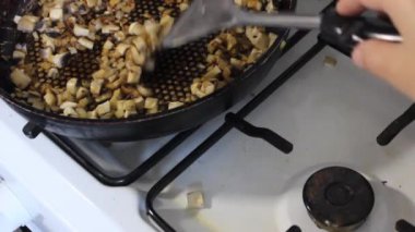 Şefin spatula ile yakın çekimi tavada doğranmış şampiyon mantarlarını engelliyor. Sağlıklı sebze yemeği pişirmek.. 